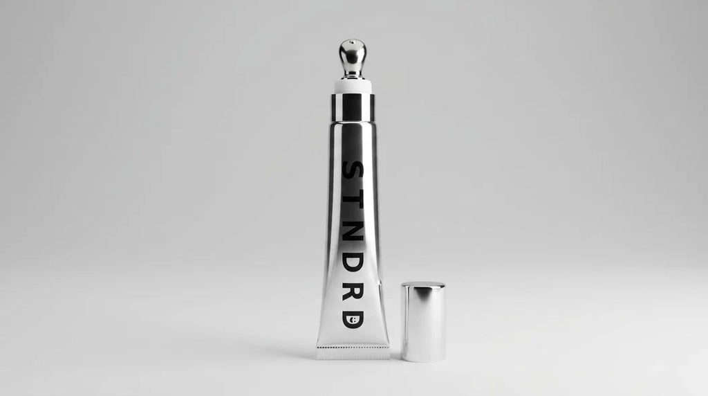 STNDRD lip balm tube standing open with the cap removed beside it